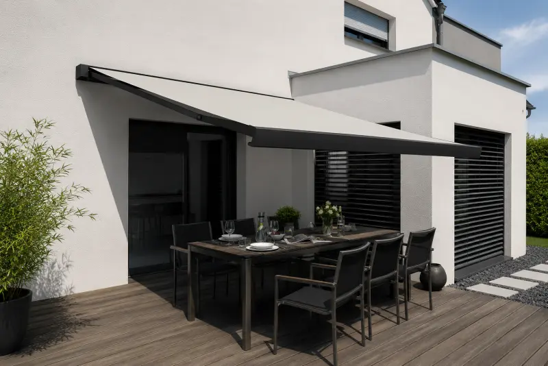 Anthrazitfarbene Markise über einer modernen Holzterrasse mit Esstisch